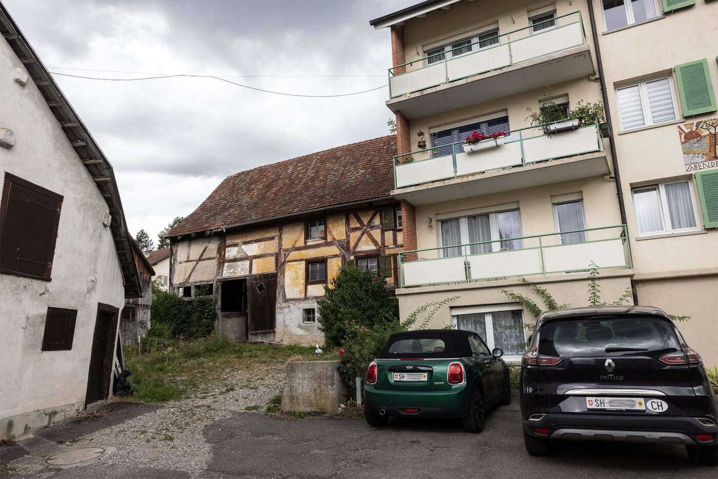 Zerfallendes Riegelhaus neben Wohnblöcken aus den Sechzigerjahren im Dorfkern von Schleitheim
